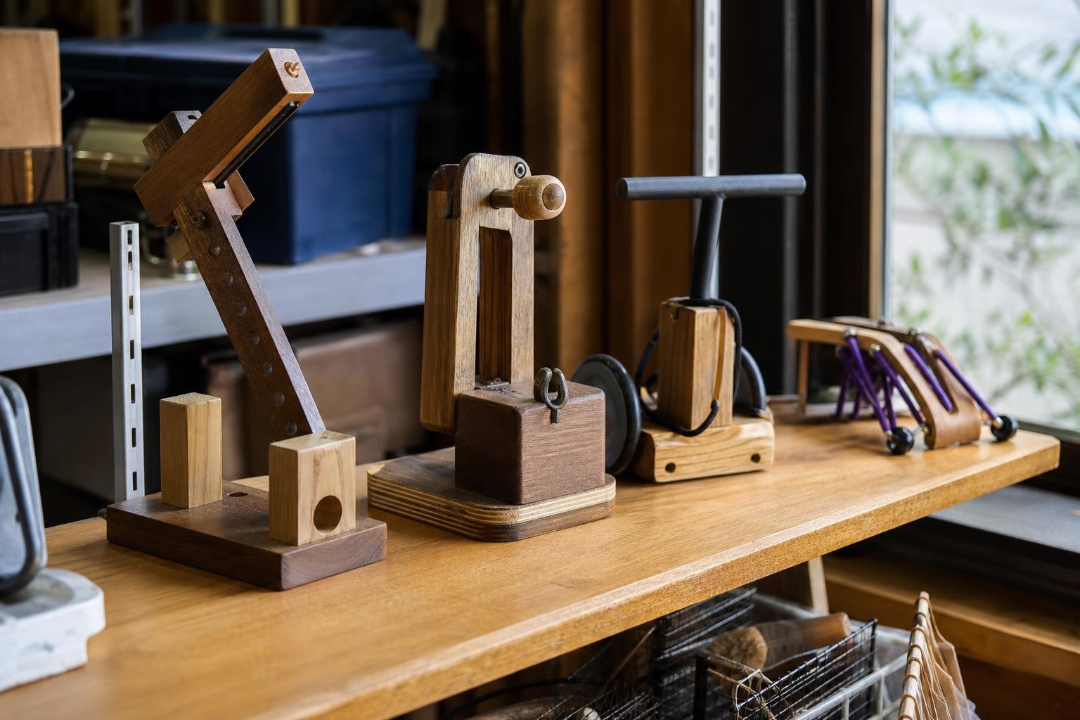 Varios objetos de madera hechos a mano, cada uno distinto, exhibidos prolijamente sobre un estante de un mostrador de préstamo de herramientas